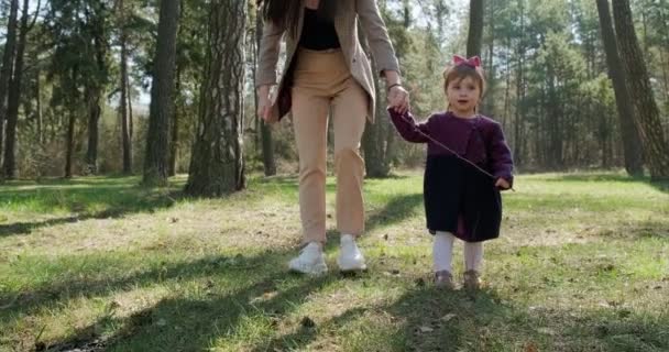 Niña feliz caminando y jugando con la madre entre los árboles en el bosque de coníferas. Recreación familiar de niños sanos en aislamiento social. Bosque de primavera belleza — Vídeos de Stock