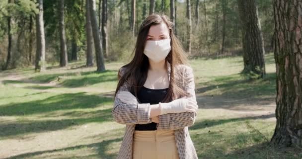 Портрет молодой женщины в защитной маске в хвойном лесу. Защита, ковид-19, коронавирус, вирус, пандемия, социальная изоляция — стоковое видео