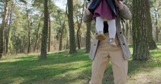 Bonne petite fille marchant et jouant avec la mère parmi les arbres dans la forêt de conifères. Enfants en santé loisirs familiaux dans l'isolement social. Printemps forêt beauté 