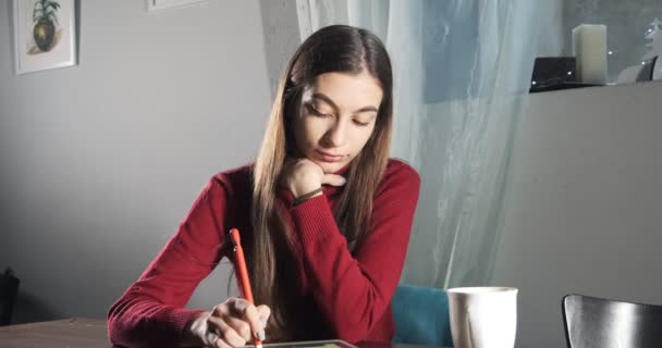 Talentueuse créatrice innovante jolie assise et travaillant à la maison. Jeune femme contemporaine écrivant, dessinant et utilisant un stylo avec tablette numérique. Attractive fille crée des illustrations numériques — Video