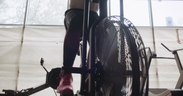 Träning med intensiv cardio cykel, motion i stängt gym. Män som gör svår konditionsträning med airbike — Stockvideo
