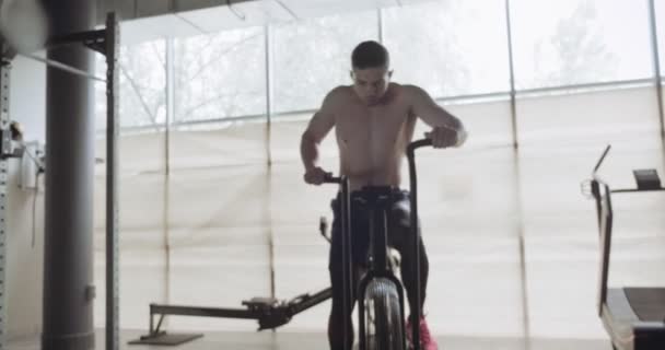 Pelatihan dengan motor kardio intens, latihan di gym tertutup. Pria yang melakukan latihan kardio sulit dengan sepeda udara — Stok Video