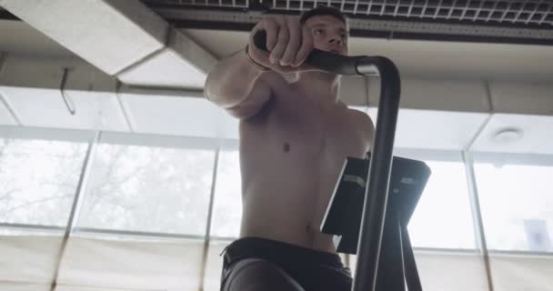 Träning med intensiv cardio cykel, motion i stängt gym. Män som gör svår konditionsträning med airbike — Stockvideo