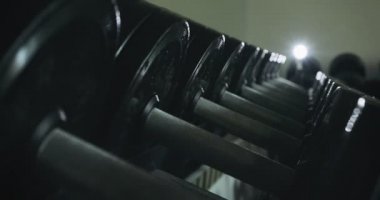 Modern spor kulübü spor salonunda dambıllar kürek çekiyor. Spor malzemelerini kapatın.