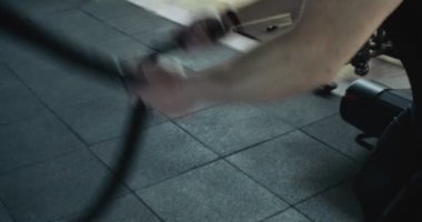 Savaş halatlarıyla antrenman, kapalı spor salonunda yoğun güç egzersizi. Erkekler halatla idman yapıyor.