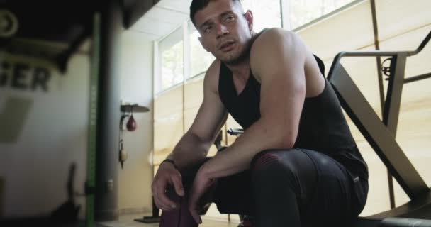 Portret van professionele gespierde atletische man bodybuilder in shorts zit op bank in gesloten fitnessruimte — Stockvideo