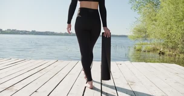 Joven rubia practicando yoga en la litera de madera en el lago. Solo deporte entrenamiento saludable en la naturaleza en tiempo soleado — Vídeos de Stock