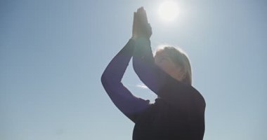 Genç sarışın kadın göldeki ahşap ranzada yoga yapıyor. Güneşli havalarda tek spor doğa üzerine sağlıklı eğitim