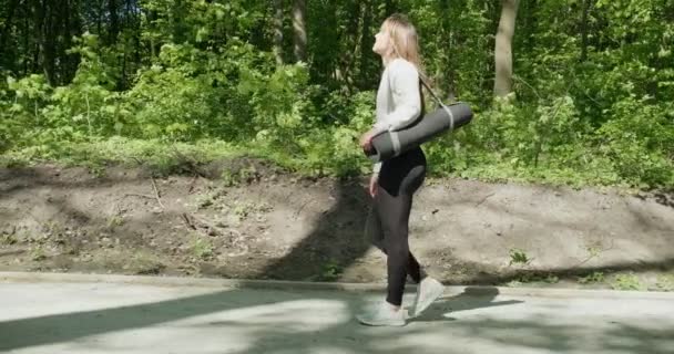 Junges Mädchen geht zum Yoga-Training in der Natur ruhige Stimmung. Frau entspannt sich in einem städtischen Naturpark. Zeitlupe — Stockvideo