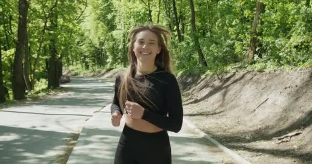 Jonge vrouw runner training in zomerpark. Close-up van fitness vrouw hardlopen in de ochtend buiten — Stockvideo