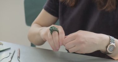Kadın oyuncak bebek seramiği yapıyor. Kadın evde oturuyor ve masada bebek için kulak yapıyor. Çömlek bebekleri parçaları, el yapımı ve yaratıcı yetenekler