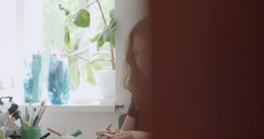 Kadın oyuncak bebek seramik parçası yapıyor. Kadın evde oturuyor ve masada bebek için kulak yapıyor. Çömlek bebekleri parçaları, el yapımı ve yaratıcı yetenekler