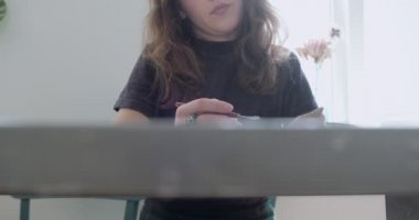 Kadın oyuncak bebek seramik parçası yapıyor. Kadın evde oturuyor ve masada bebek için kulak yapıyor. Çömlek bebekleri parçaları, el yapımı ve yaratıcı yetenekler