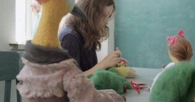 Masada yün oyuncak bebek yapan bir kadın. Kadın evde oturup meşe bebek yapıyor. İğne Keçeli El yapımı ve yaratıcı yetenekler