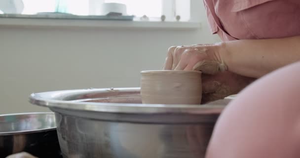 Kvinnlig krukmakare sitter och gör en kopp på keramik hjulet. Kvinna gör keramiska objekt. Keramik arbete, handgjorda och kreativa färdigheter — Stockvideo