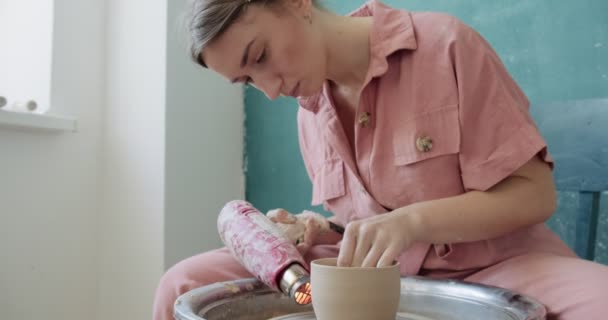 Femme potier assis et tirant une forme tasse d'argile sur la roue de poterie. Femme fabriquant des articles en céramique. Poterie cuisson, à la main et des compétences créatives — Video