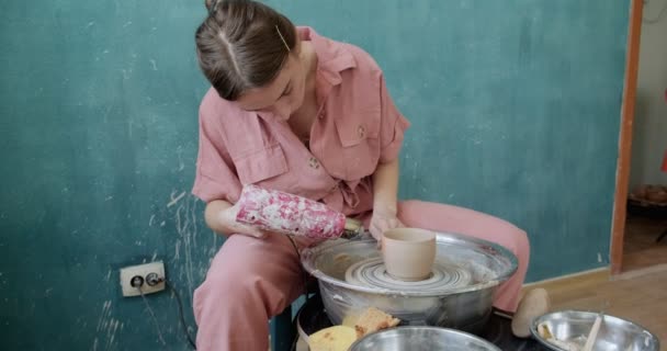 Γυναίκα αγγειοπλάστη κάθεται και ψήσιμο ένα σχήμα κύπελλο πηλό στον κεραμικό τροχό. Γυναίκα που φτιάχνει κεραμικά αντικείμενα. Ψήσιμο κεραμικών, χειροποίητες και δημιουργικές δεξιότητες — Αρχείο Βίντεο