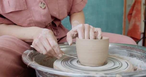 Alfarero hembra sentado y hace una taza en la rueda de cerámica. Mujer haciendo artículo de cerámica. Trabajo de cerámica, habilidades hechas a mano y creativas — Vídeo de stock