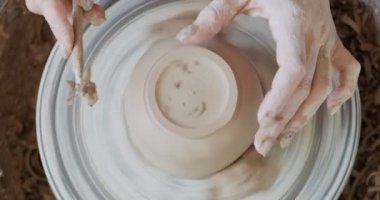 Kadın çömlekçi oturuyor ve çömlek çarkında bir fincan yapıyor. Kadın seramik bir şey yapıyor. Çömlekçilik, el yapımı ve yaratıcı beceriler