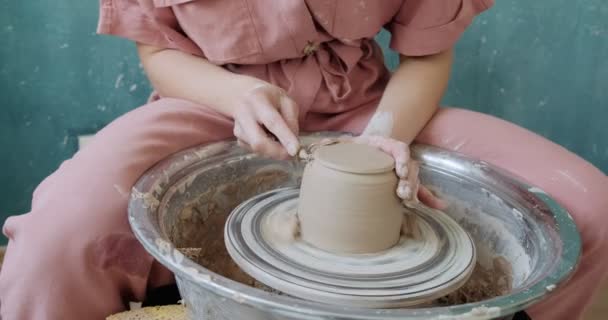 Alfarero hembra sentado y hace una taza en la rueda de cerámica. Mujer haciendo artículo de cerámica. Trabajo de cerámica, habilidades hechas a mano y creativas — Vídeo de stock