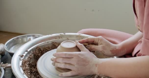 Female potter sitting and makes a cup on the pottery wheel. Woman making ceramic item. Pottery working, handmade and creative skills — Stock Video