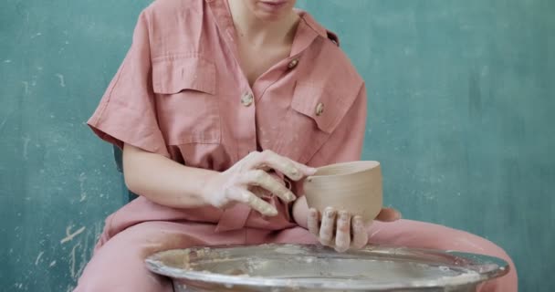 Ceramista donna seduta e fa una tazza. Donna che fa oggetti in ceramica. Lavorazione della ceramica, abilità artigianali e creative — Video Stock