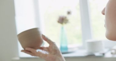 Dişi çömlekçi oturuyor ve bir fincan yapıyor. Kadın seramik bir şey yapıyor. Çömlekçilik, el yapımı ve yaratıcı beceriler