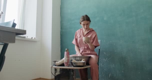 Alfarera sentada y haciendo una taza. Mujer haciendo artículo de cerámica. Trabajo de cerámica, habilidades hechas a mano y creativas — Vídeo de stock