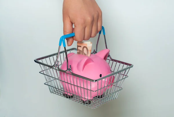 Kumbara ile alışveriş sepeti tutan el