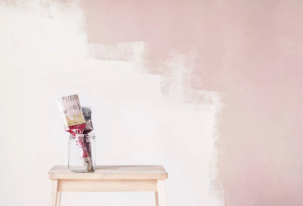 Huisreparatie, penselen in glas met beschilderde wand op de achtergrond — Stockfoto