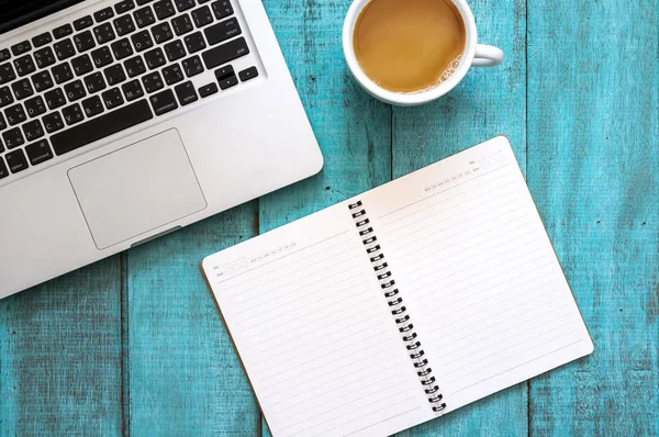 Blue wooden desk table with computer laptop, notebook and cup of — Stock Photo, Image