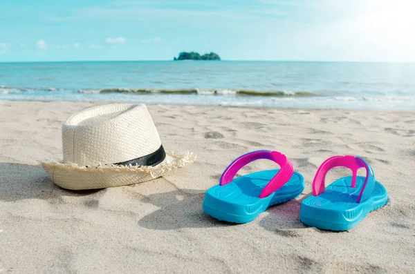 Hasır şapka ve güneşli gökyüzü karşı sahilde renkli flip flop. — Stok fotoğraf