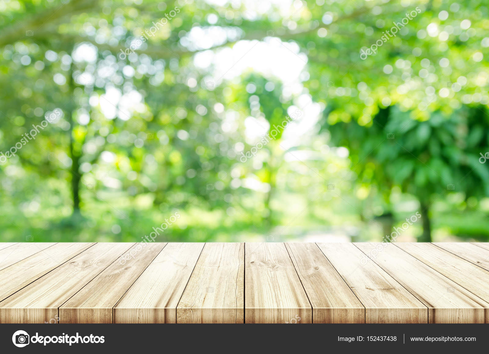 Empty wooden table top with blurred green natural background. Stock