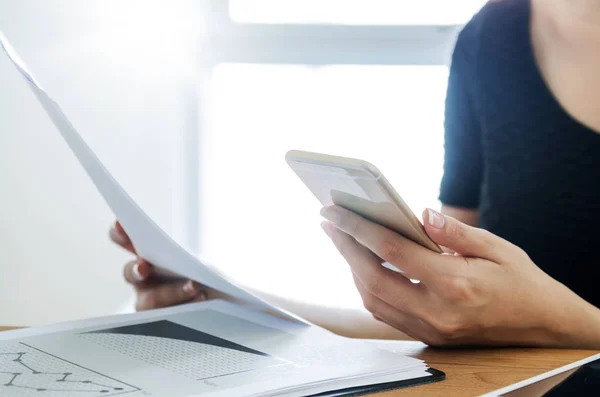 Mujer sosteniendo documento móvil y financiero en su escritorio . — Foto de Stock