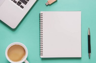 Ofis işyeri kavramı. Bilgisayar dizüstü bilgisayar boş dizüstü bilgisayar, fincan kahve, kalem, mavi arka plan üstünde birden parlamak götürmek ile.