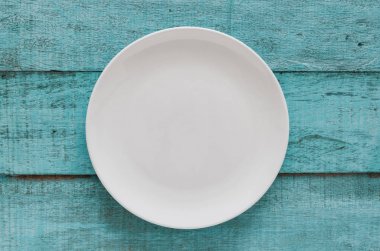 Mavi ahşap arka plan boş beyaz tabakta. Kopya alanı ile Üstten Görünüm. 