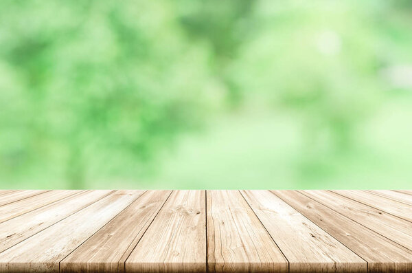 Empty wooden table top with blurred green natural abstract backg