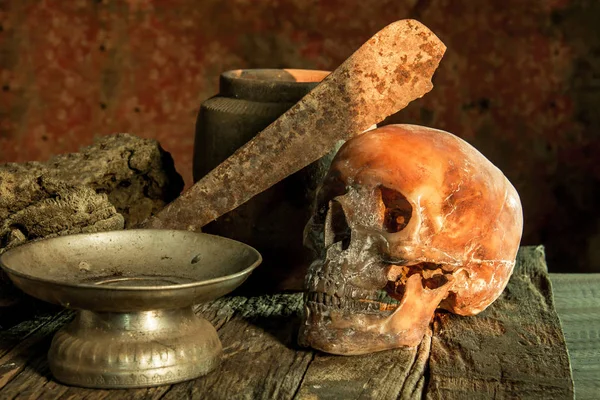 Fotografía de naturaleza muerta, cráneo humano con cuchillo viejo en la frente —  Fotos de Stock
