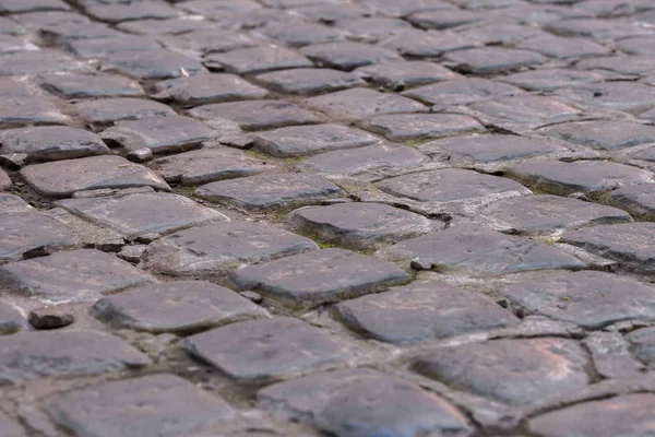 Cerca de adoquines pavimento, calle de piedra pavimento de fondo con enfoque selectivo. Textura de camino de piedra, fondo adoquinado — Foto de Stock