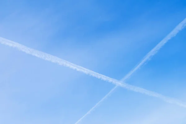 Dva protínající se kondenzační stopy letadel na jasné modré oblohy. Místo pro váš text, za použití pozadí. — Stock fotografie