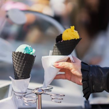 Siyah gözleme külah. Dondurma farklı türde. Kadının el ile sarı dondurma waffle koni şekerli tatlı sayaçlarıyla arka plan üzerinde tutarak. Gerçek sahne