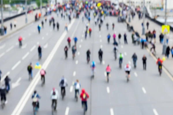 Abstract blurred background of mass cycling marathon in streets of city. Participants go back to us. Concept of Sport, healthy lifestyle, aktivity. Selective focus.