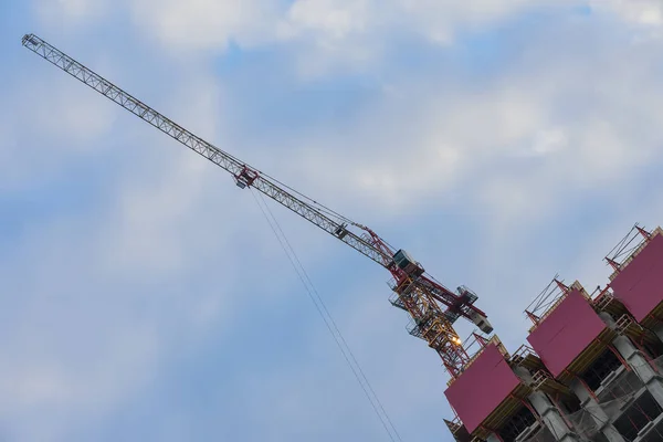 Speciaal diagonale beeld van bouw toren kraan naast gebouw in aanbouw tegen de achtergrond van de blauwe lucht. Ongewone verkorting. Kopiëren van ruimte — Stockfoto