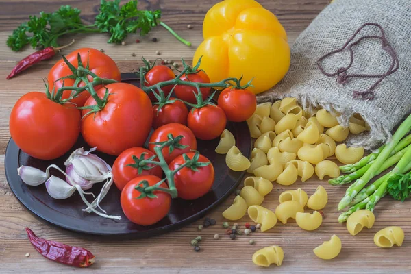 Состав для традиционной итальянской кухни - сухая паста, овощи, свежие помидоры, чеснок, спаржа, желтый перец. Концепция вегетарианская, здоровая еда. Вид сверху — стоковое фото