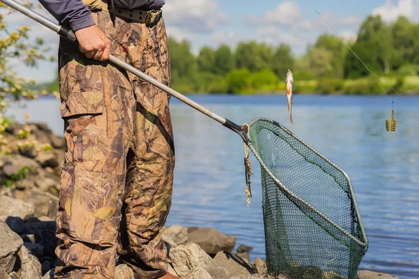 Een onherkenbaar middelbare leeftijd visser met een oude net met een gat en een kleine vers gevangen vis op de regel. Concept van actieve gezonde levensstijl op elke leeftijd — Stockfoto
