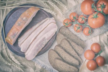 Taze organik gıda rustik tarzı. Hızlı lezzetli Aperatif. Pastırma, çavdar siyah ekmek, peçete burlar dan Olgun kırmızı domates dilimleri. Üstten görünüm. Vintage zemin