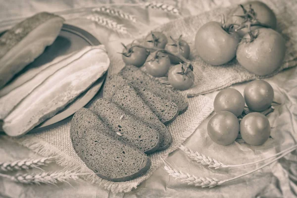 Vintage sepia style of fresh organic food. Quick traditional tasty snack. Slices of bacon, rye black bread, ripe red tomatoes on coarse burlap. Top view — Stock Photo, Image