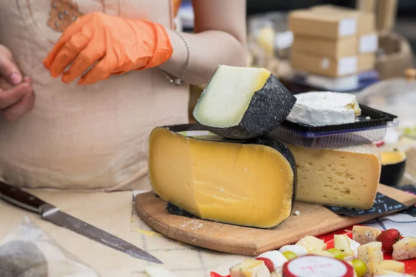 Produtos gastronómicos para gourmets, tradicionais italianos cortar cabeças de queijo no balcão do mercado, mulheres mãos de vendedor com faca — Fotografia de Stock