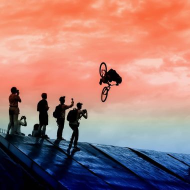 Extrem spor ve risk. Yapan genç erkek silueti ile parlak gökyüzü karşı bmx Bisiklet atlama. Birkaç fotoğrafçılar trambolin üzerinde yüksek çekim yapmak
