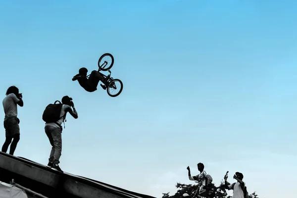 Extreme cyclists, young man doing jump with bmx bike on background of blue sky. With place for your text, for background use.